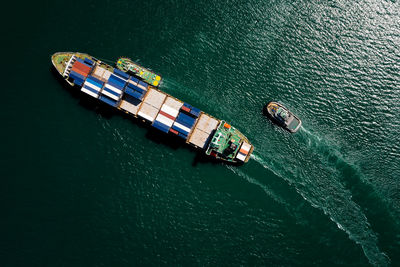 Aerial top view container ship sailing on the green sea full speed container for logistics, 