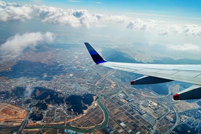 Aerial view of airplane flying over cityscape against sky