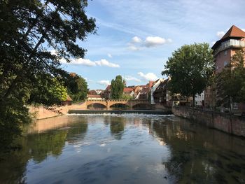 Arch bridge over river by building against sky