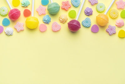 Directly above shot of multi colored candies on yellow background