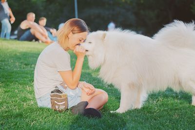 Young woman with dog sitting on grass