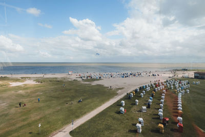 High angle view of beach with beach chairs and the ocean against blue sky