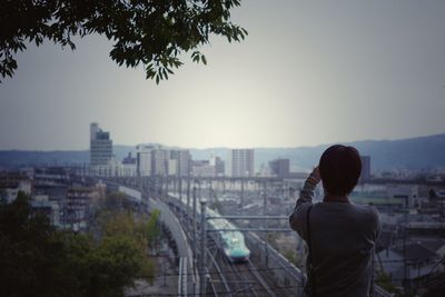 Rear view of man standing against sky in city