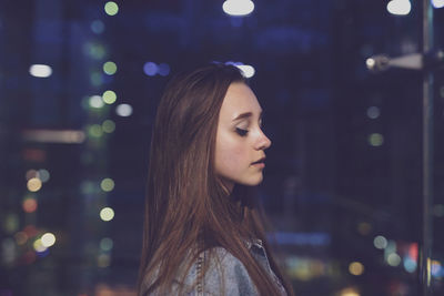 Young woman by glass window at night