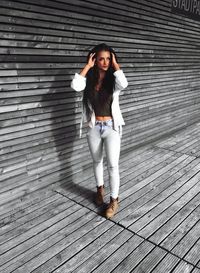 Portrait of young woman standing against brick wall