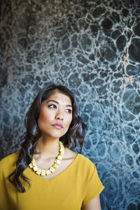 Thoughtful woman standing against designed wall