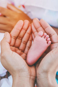 Cropped hands of mother holding baby leg