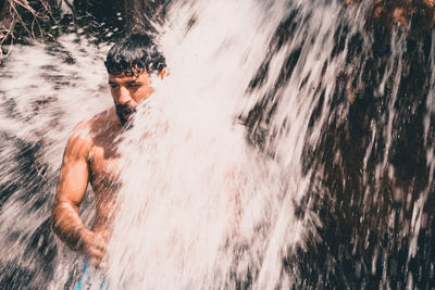 Shirtless man in waterfall