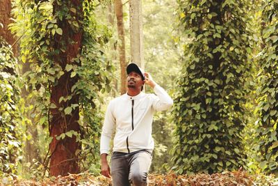 Young man standing against plants