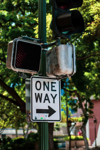 Close-up of one way sign on pole against trees