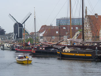 Sailboats moored on river by buildings in city