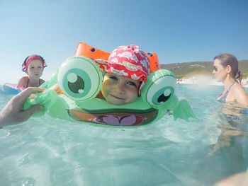 Portrait of boy swimming with family in sea against clear sky