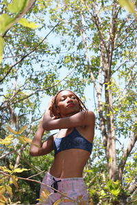 Low angle view of woman standing by tree against plants