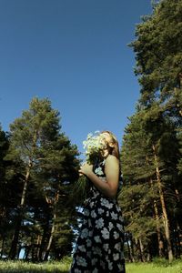 Woman standing by tree against clear sky