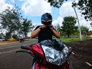 Man wearing helmet while sitting on motorcycle against trees