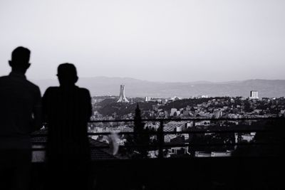 Rear view of silhouette man and cityscape against sky