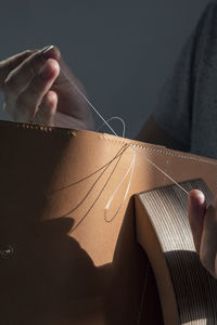 Midsection of man stitching cardboard