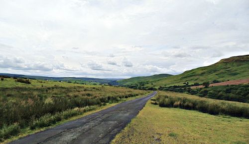 Road amidst field against sky