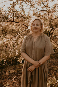 Portrait of young woman standing against trees