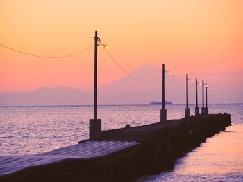 Scenic view of suspension bridge over sea against sky during sunset