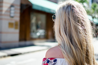 Side view of woman with blond hair standing on street