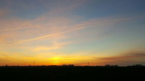 Scenic view of silhouette field against sky at sunset