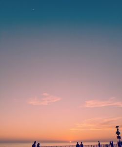 Silhouette people on beach against sky during sunset