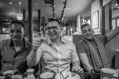 Cheerful young male friends having food at restaurant