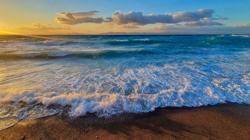 Sea horizon and wave at sunset hitting the beach.