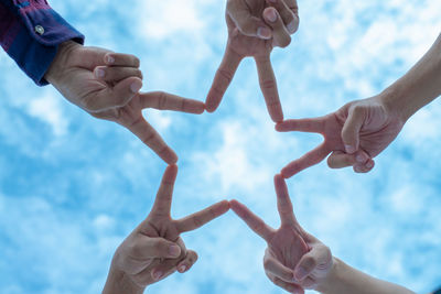 Low angle view of people hands against sky