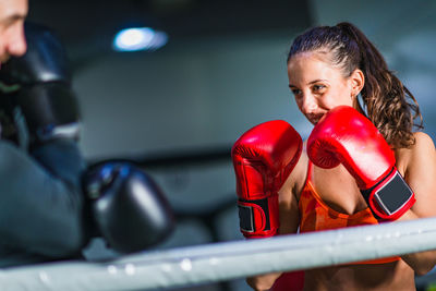 Female boxer practicing with male coach in gym