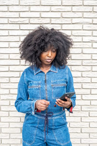 Young woman standing against brick wall