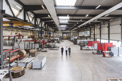 Three men walking and talking on factory shop floor