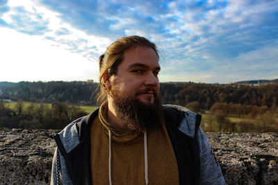 Portrait of young man standing against sky