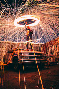 Blurred motion of man with light trails against sky at night