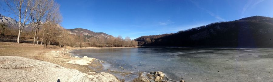 Scenic view of lake and mountains against clear blue sky