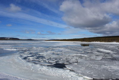 Frozen lake against cloudy sky