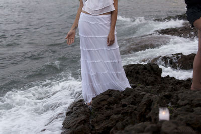 Low section of woman standing on sea shore