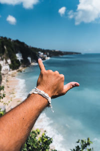 Low angle view of hand against sea against sky