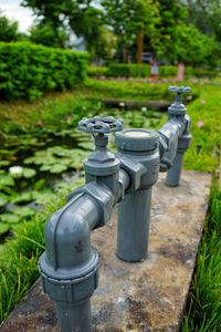 Close-up of water pipe on grass against trees