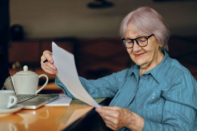 Senior woman reading document while sitting in cafe