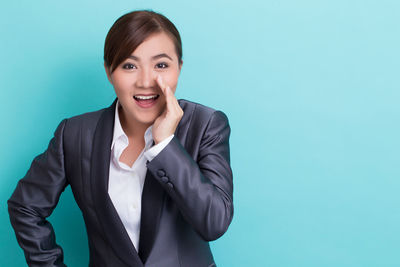 Portrait of a smiling young woman against blue background