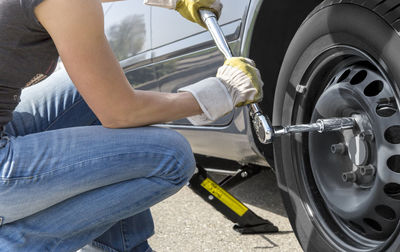 Midsection of woman repairing car on road