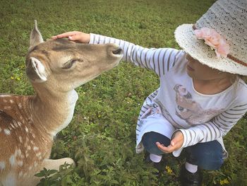 Full length of hand feeding horse on field