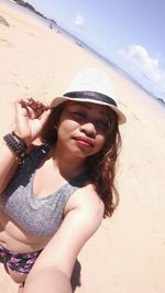 Portrait of smiling young woman on beach against sky