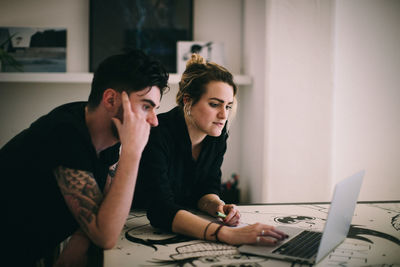 Business people discussing over laptop at desk in creative office