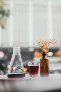 Black coffee by flowers in bottle on table