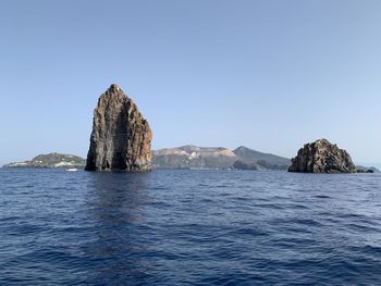 Scenic view of rock formation in sea against clear sky