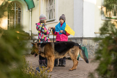 Two little girls with the flag of ukraine, suitcase, dogs. ukraine war migration. 