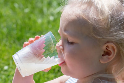 Close-up of cute girl drinking juice in park during sunny day